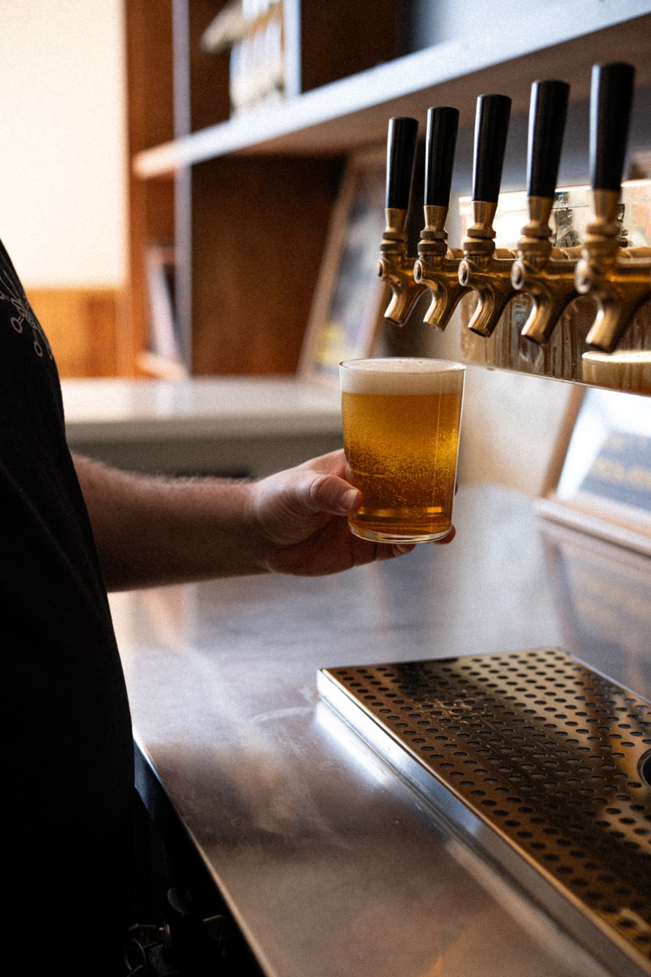 Bartender pouring a golden beer from brass draft taps